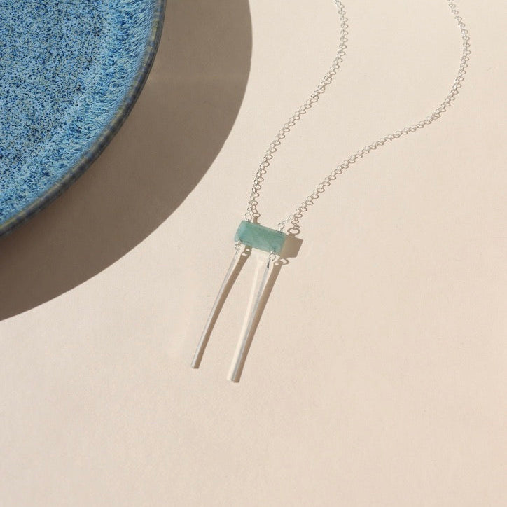 sterling silver dainty chain necklace with rectangle aquamarine bead & 2 sterling silver bars on a light background