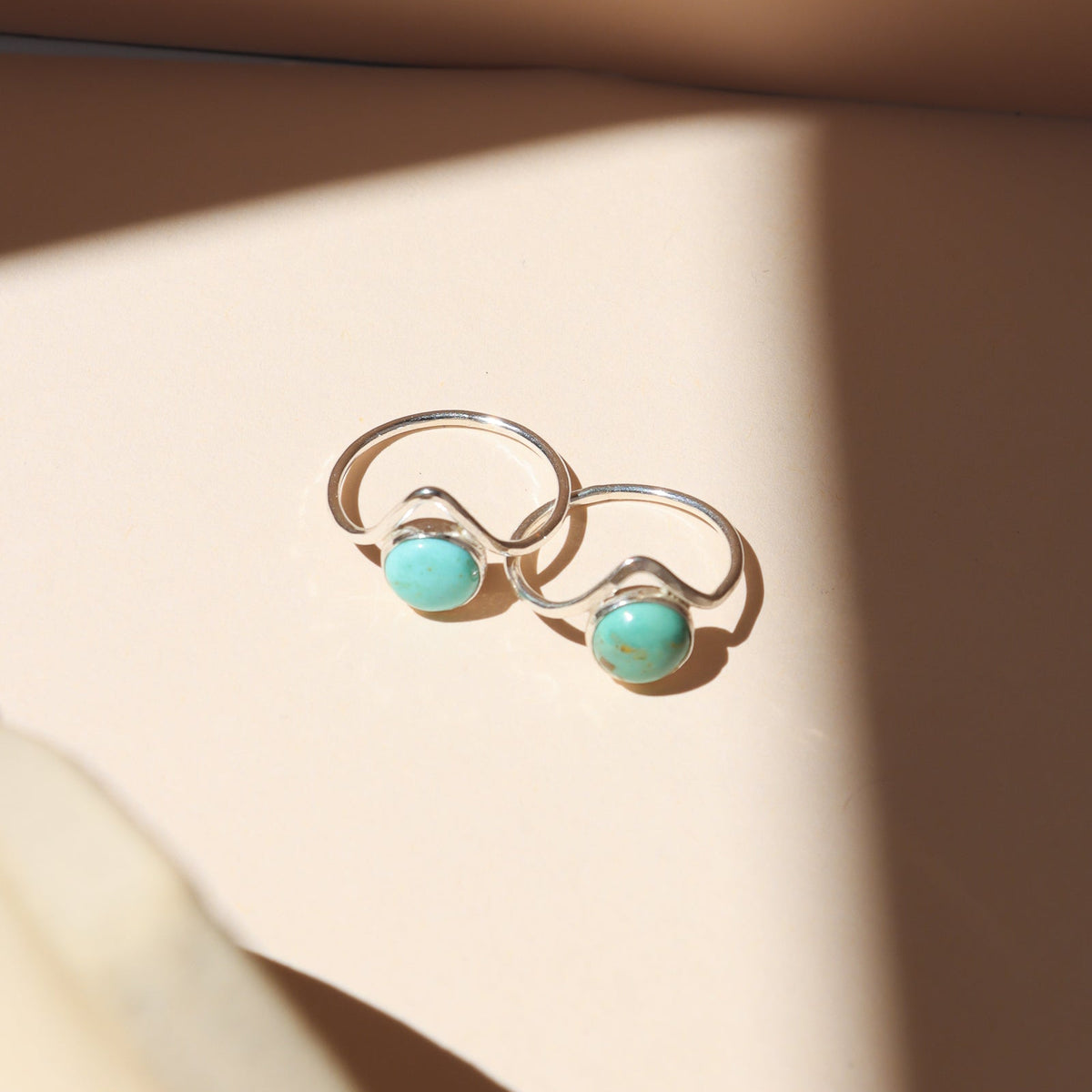 sterling silver rings with point and round turquoise stone on a light dish