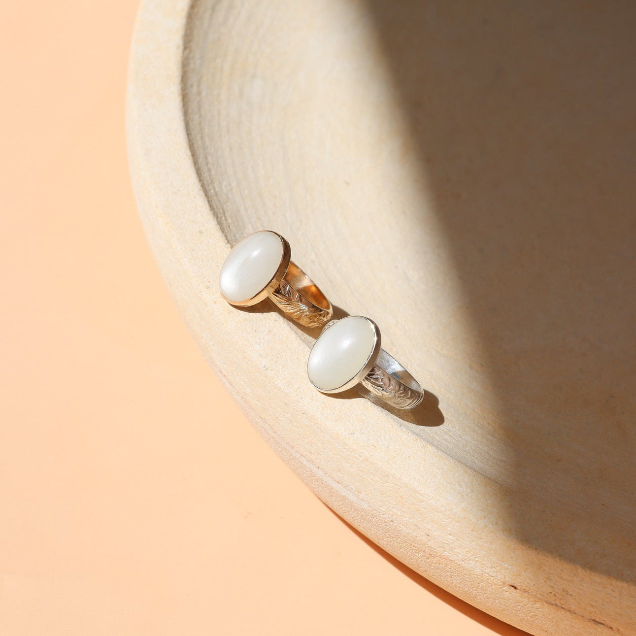14k gold fill and sterling silver rings with oval moonstones on a light dish
