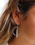 Model wearing a sterling silver hoop featuring white opal gemstones dropped 2" from earring post. 