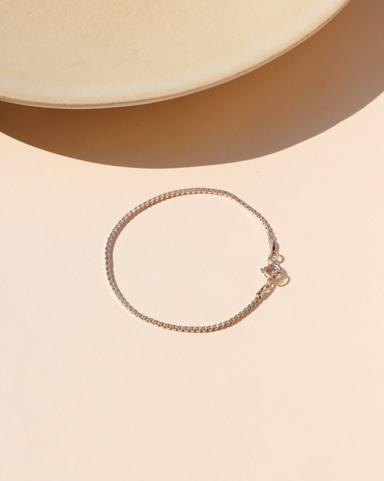 sterling silver box chain bracelet on a light dish in the sunlight
