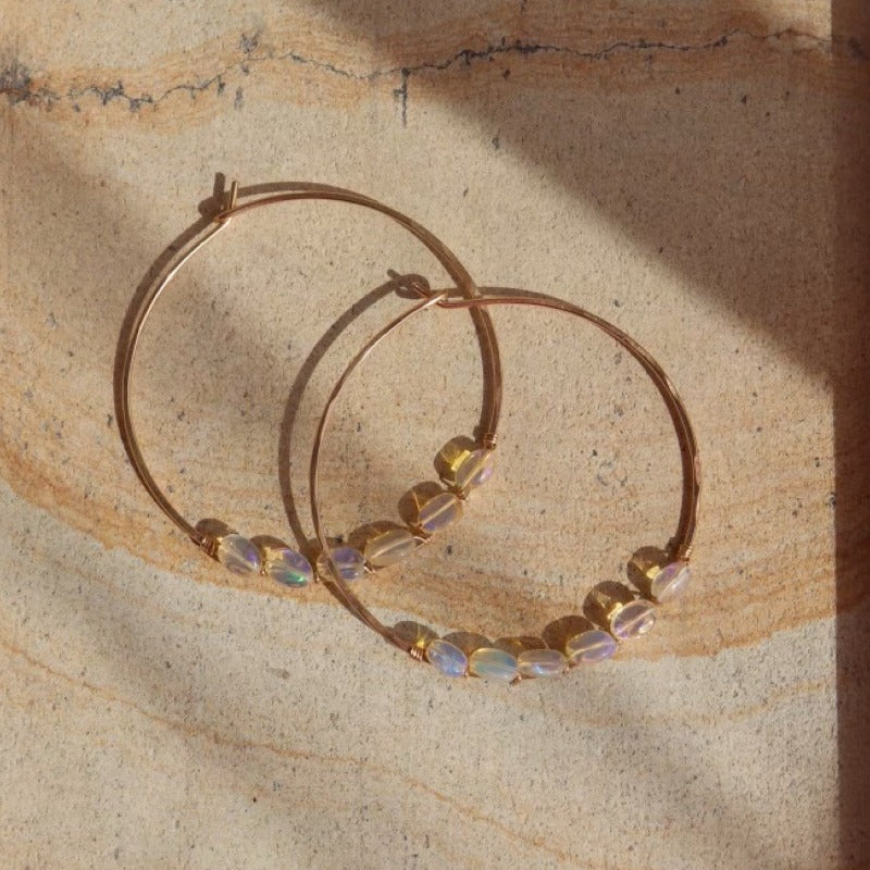 14k gold fill or sterling silver hoops, handmade and lightly hammered for shine, then adorned with six genuine australian opals that are delicately wire-wrapped. Handmade by Token Jewelry in Eau Claire, WI