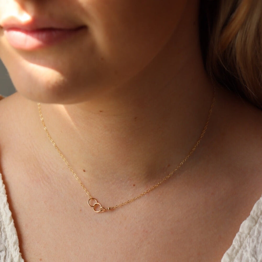 14k gold fill Lineage Necklace placed on a white jewelry dish. This necklace features jump rings representing parents, kids, and others you are able to pick the sizing of each jump ring.