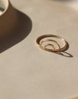 14k gold fill Rainbow Ring ring place on a tan plate in the sunlight.