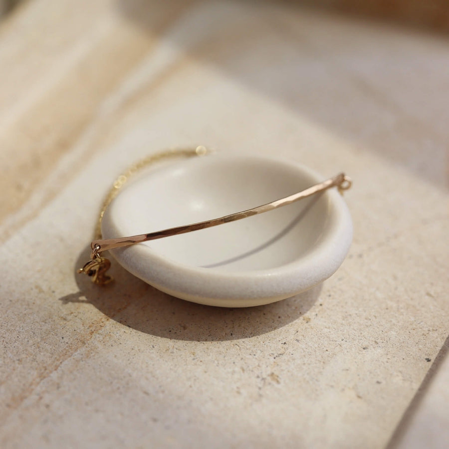 14k gold fill Bar Anklet laid on a tan ring dish in the sunlight- Token Jewelry