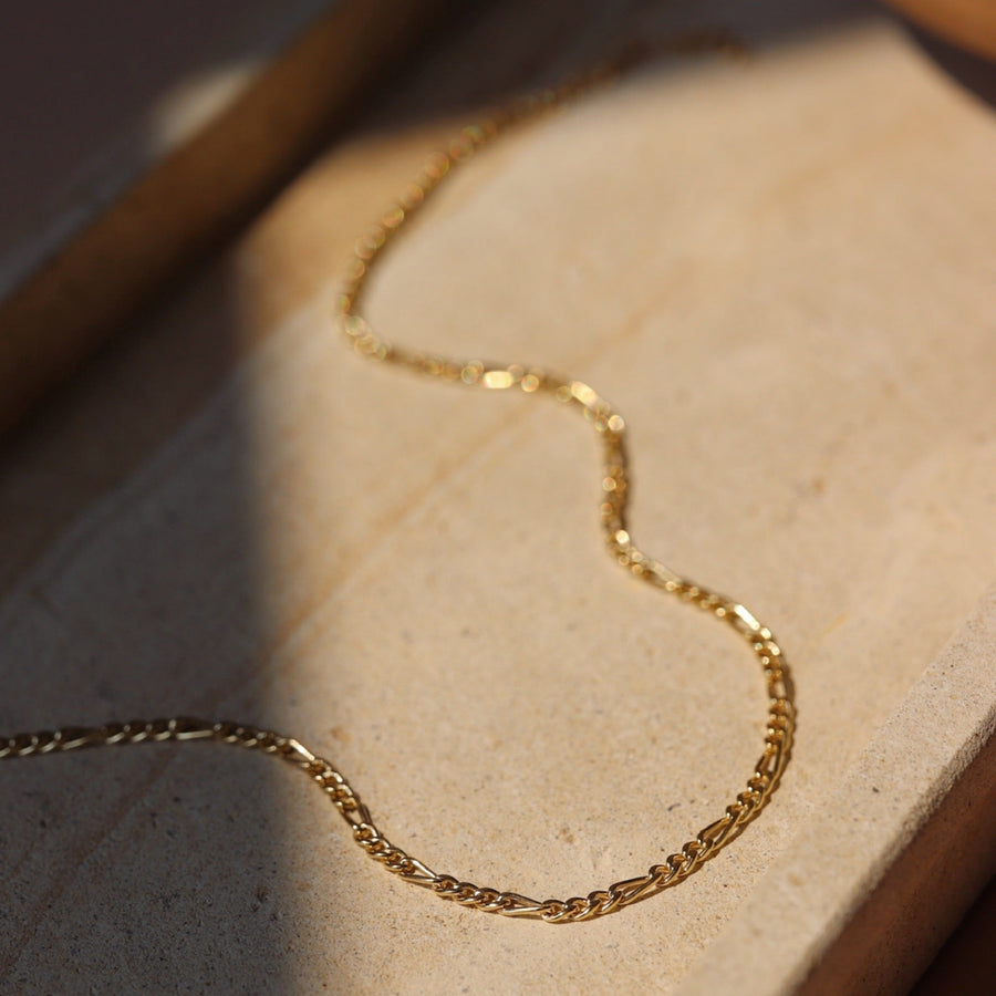 14k gold fill Gigi necklace layer on a cream colored plate. 