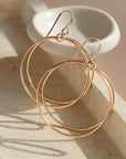 14k gold fill Parallel Hoops placed on a stone plate in the sunlight. - Token Jewelry